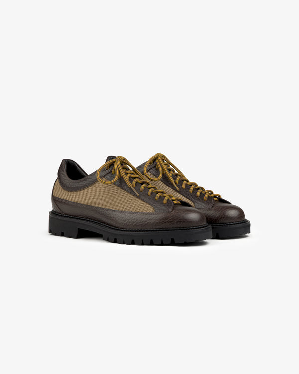 Field Boot low-top hiking shoes with brown leather overlays, tan mesh panels, and yellow laces on black lugged soles.