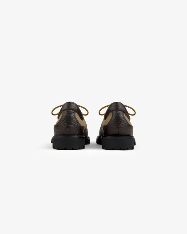 Back view of Field Boot shoes in dark brown and tan with thick, black lugged rubber soles.