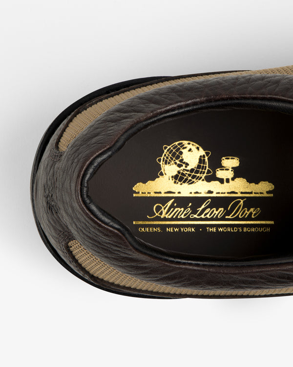 Top-down view of a brown leather Field Boot interior with a gold Aimé Leon Dore globe logo, Queens, NY.
