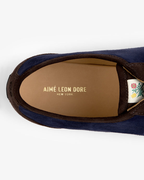 Top-down view of a navy Low Profile Suede Trainer showing the interior heel branding and a small floral tongue tag.