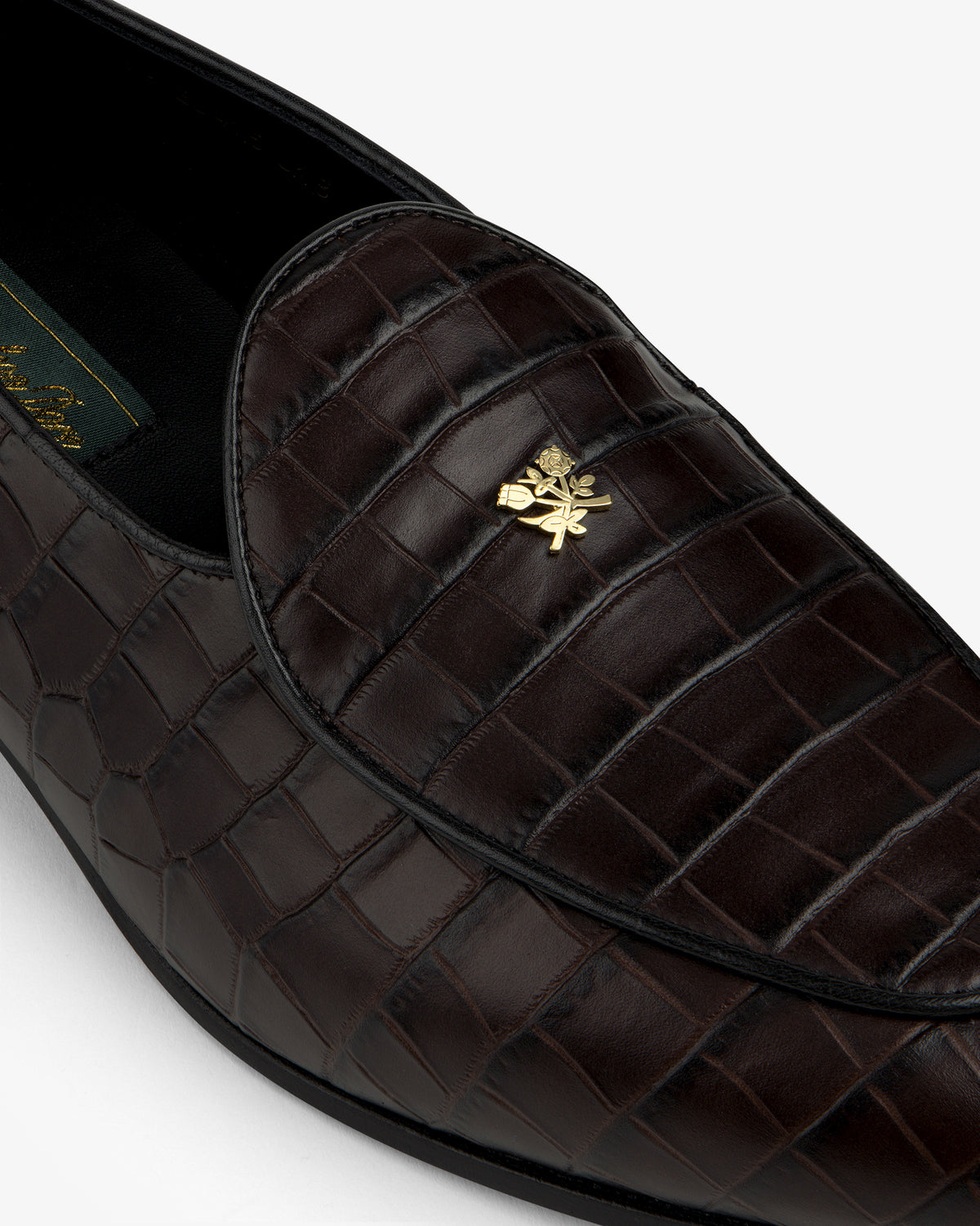 Close-up of Croc-Embossed Crest Salóni Loafer in dark brown with a gold emblem on the upper.