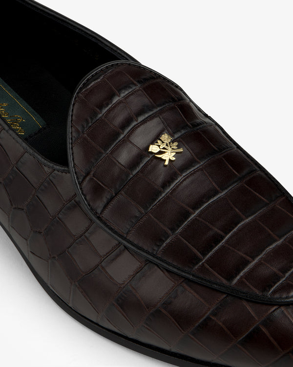 Close-up of Croc-Embossed Crest Salóni Loafer in dark brown with a gold emblem on the upper.