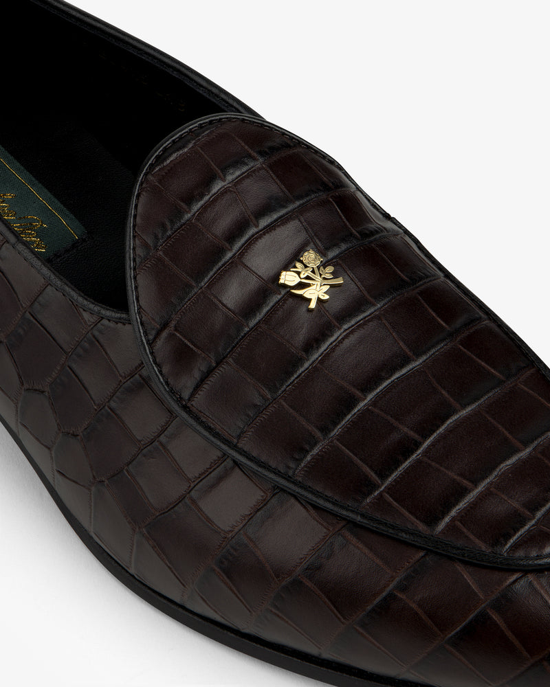 Close-up of Croc-Embossed Crest Salóni Loafer in dark brown with a gold emblem on the upper.