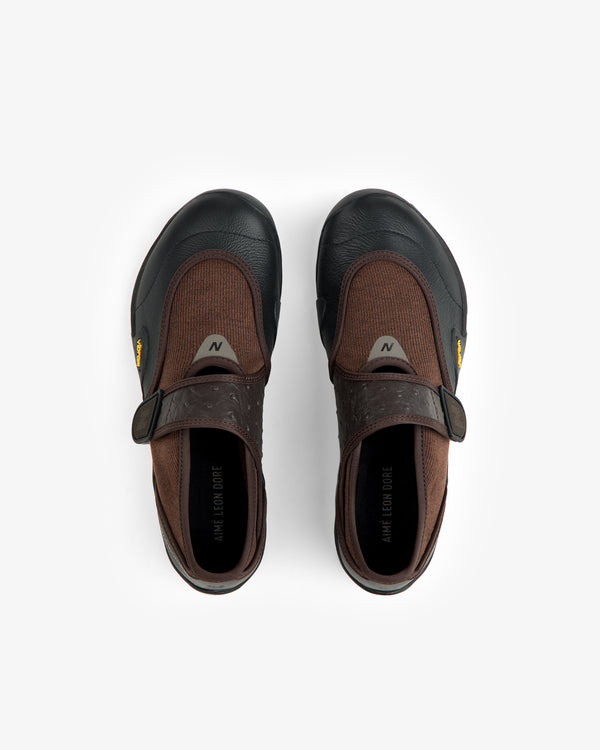 ALD / New Balance MT2 brown and black slip-on shoes with a hook-and-loop strap and textured rubber outsoles.