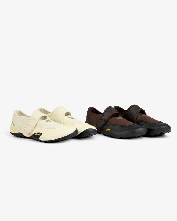 ALD / New Balance MT2 low-profile slip-on sneakers with velcro straps and black rubber soles, in cream and brown.