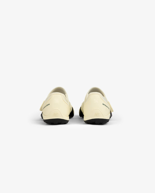 Back view of two cream-colored ALD / New Balance MT2 slip-on shoes with black rubber soles.