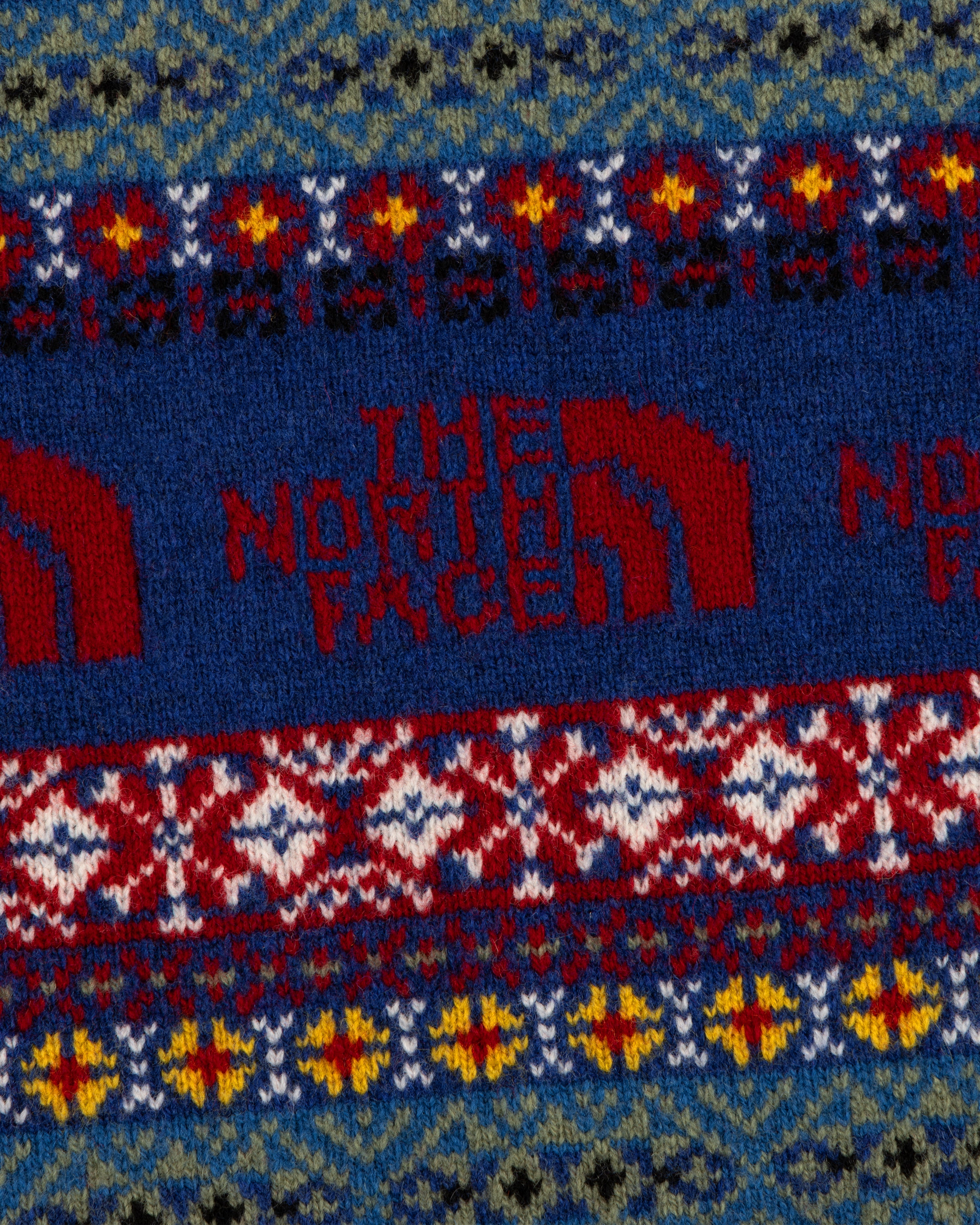 Close-up of the ALD / The North Face Fair Isle Scarf with a red logo amid blue, red, yellow, and white patterns.