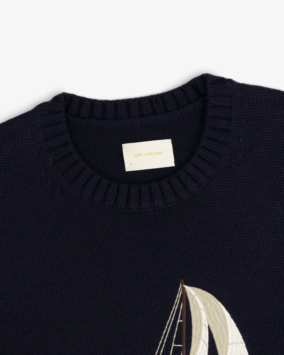 Regatta Embroidered Crewneck Sweater in navy blue with a ribbed collar and partial sailboat embroidery at hem.