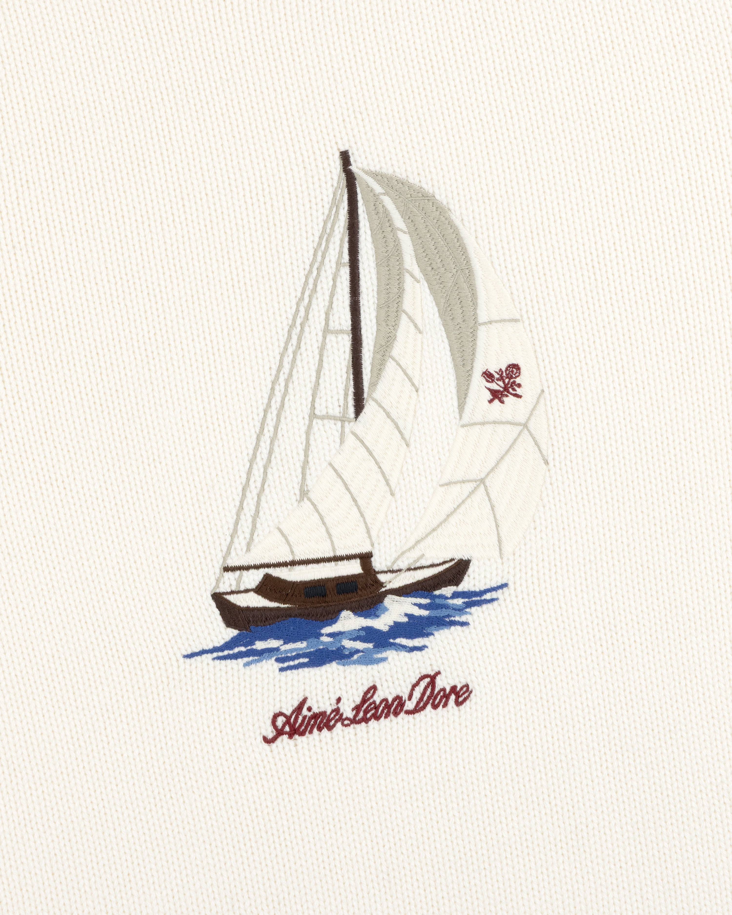 Regatta Embroidered Crewneck Sweater: Sailboat with white sails on blue water, Aimé Leon Dore text, cream fabric.