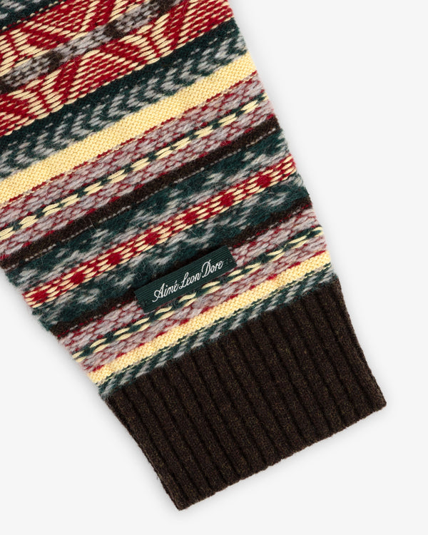A Fair Isle V-Neck Sweater sleeve features multicolored knit, a ribbed brown cuff, and an Aimé Leon Dore label.