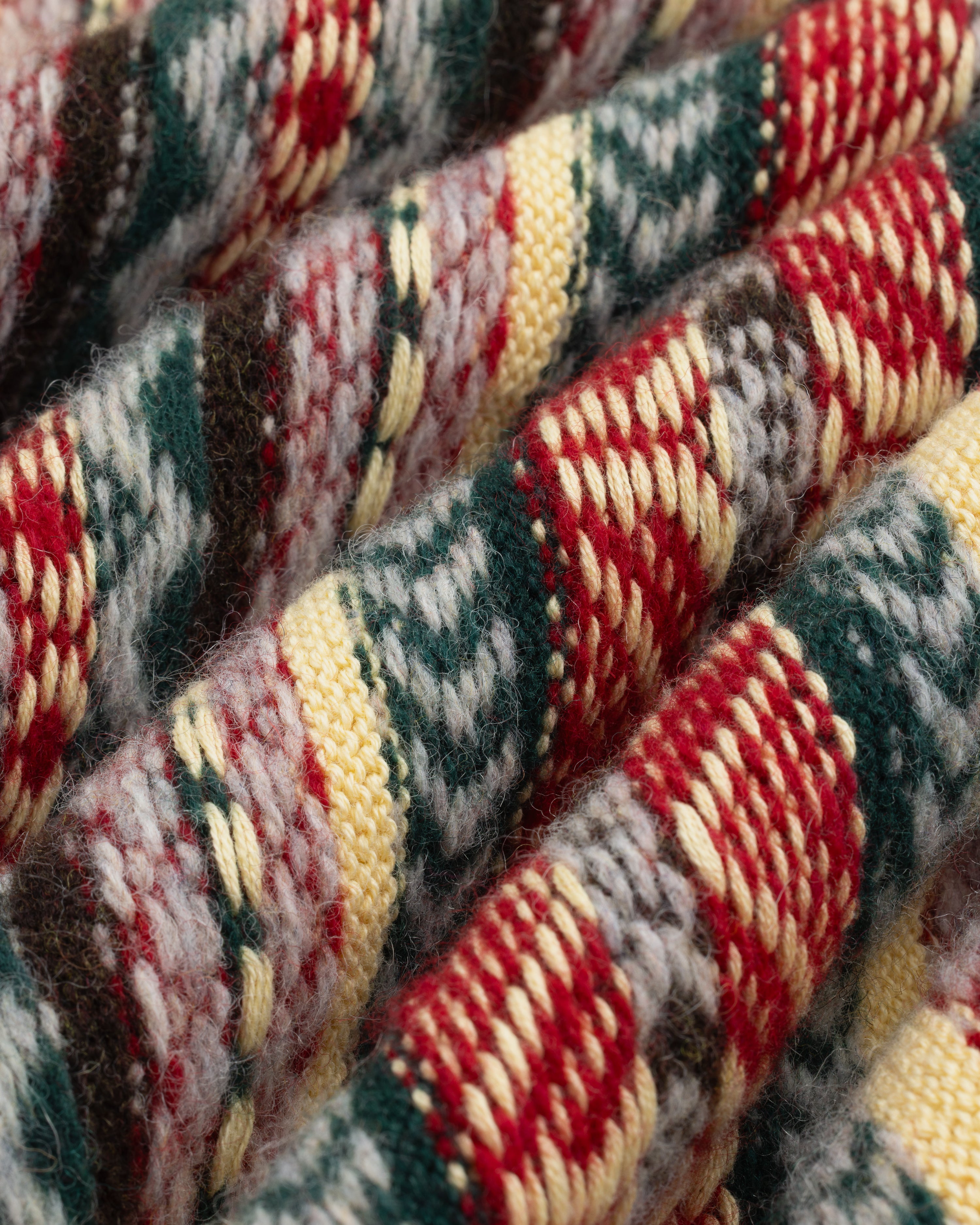 Close-up of Fair Isle V-Neck Sweater knit with red, green, yellow, and white patterns in textured rows.