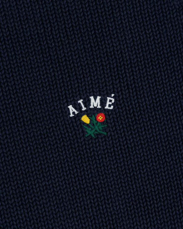 Navy Crest Raglan Sweater with AIMÉ embroidered above a yellow and red flower design.