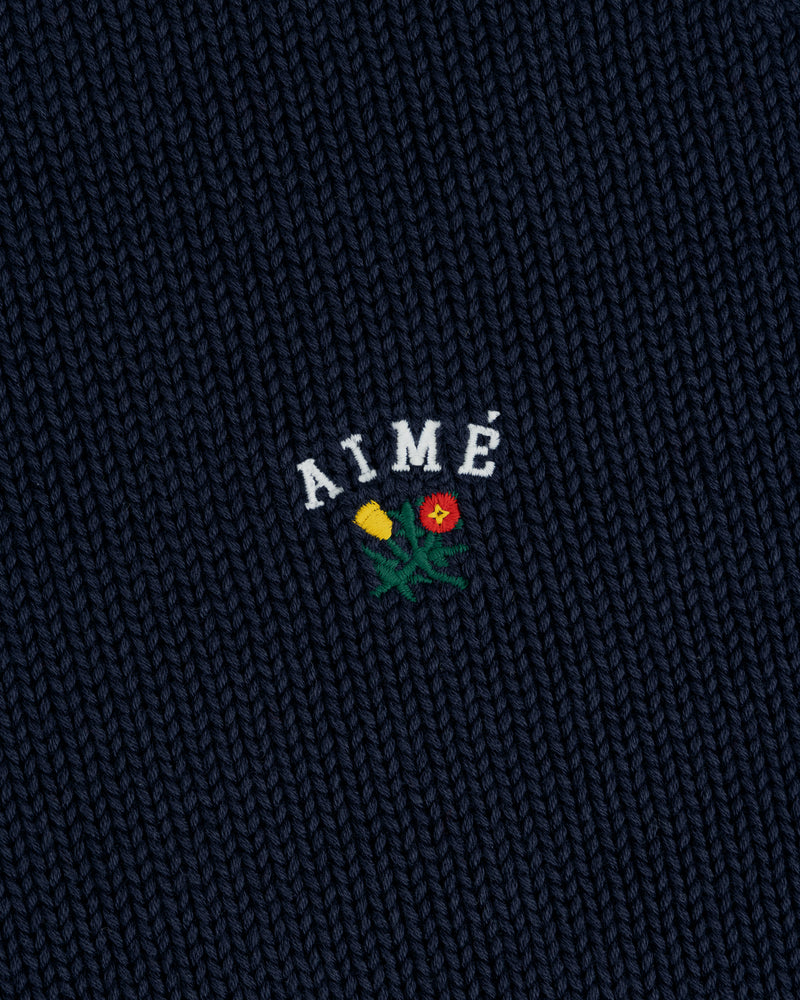 Navy Crest Raglan Sweater with AIMÉ embroidered above a yellow and red flower design.