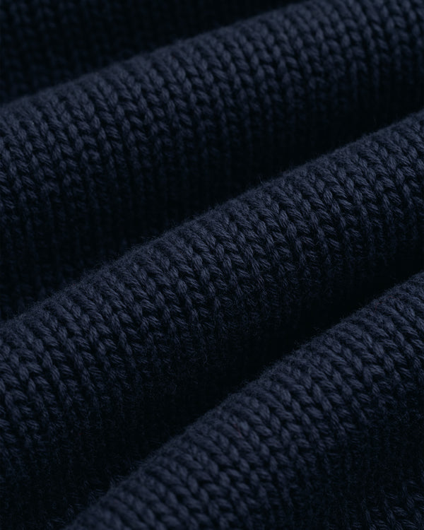 Close-up of the Crest Raglan Sweater in dark blue, showing its textured rows and visible knitted stitches.