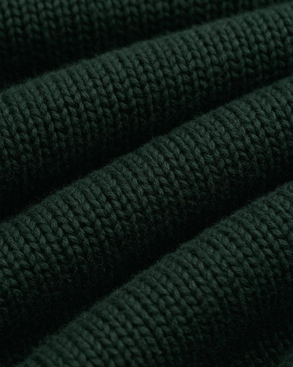 Close-up of Crest Raglan Sweater: dark green ribbed knit with textured horizontal rows and soft fibers.