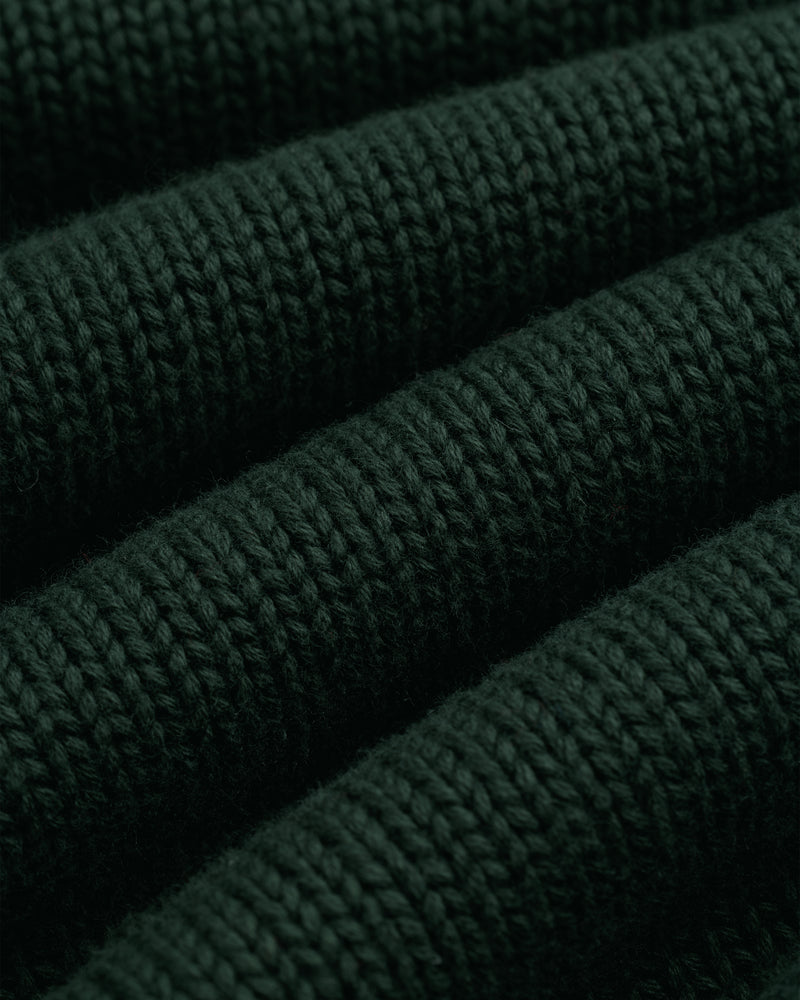 Close-up of Crest Raglan Sweater: dark green ribbed knit with textured horizontal rows and soft fibers.