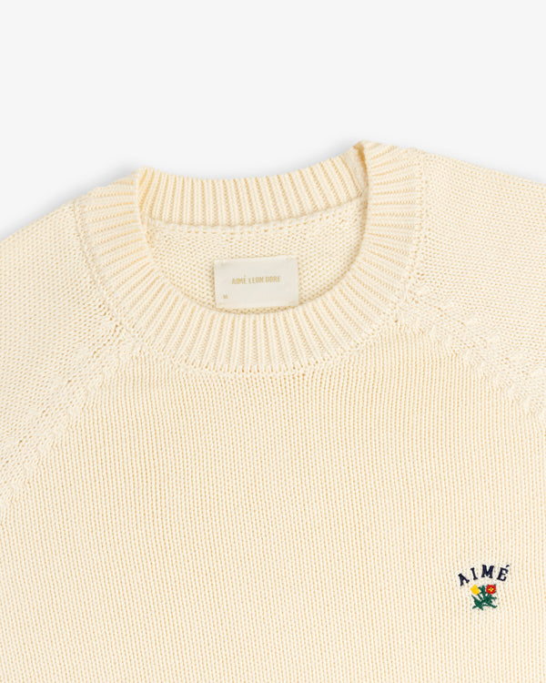 Crest Raglan Sweater: Cream knit crewneck with small AIME and floral embroidery on left chest.