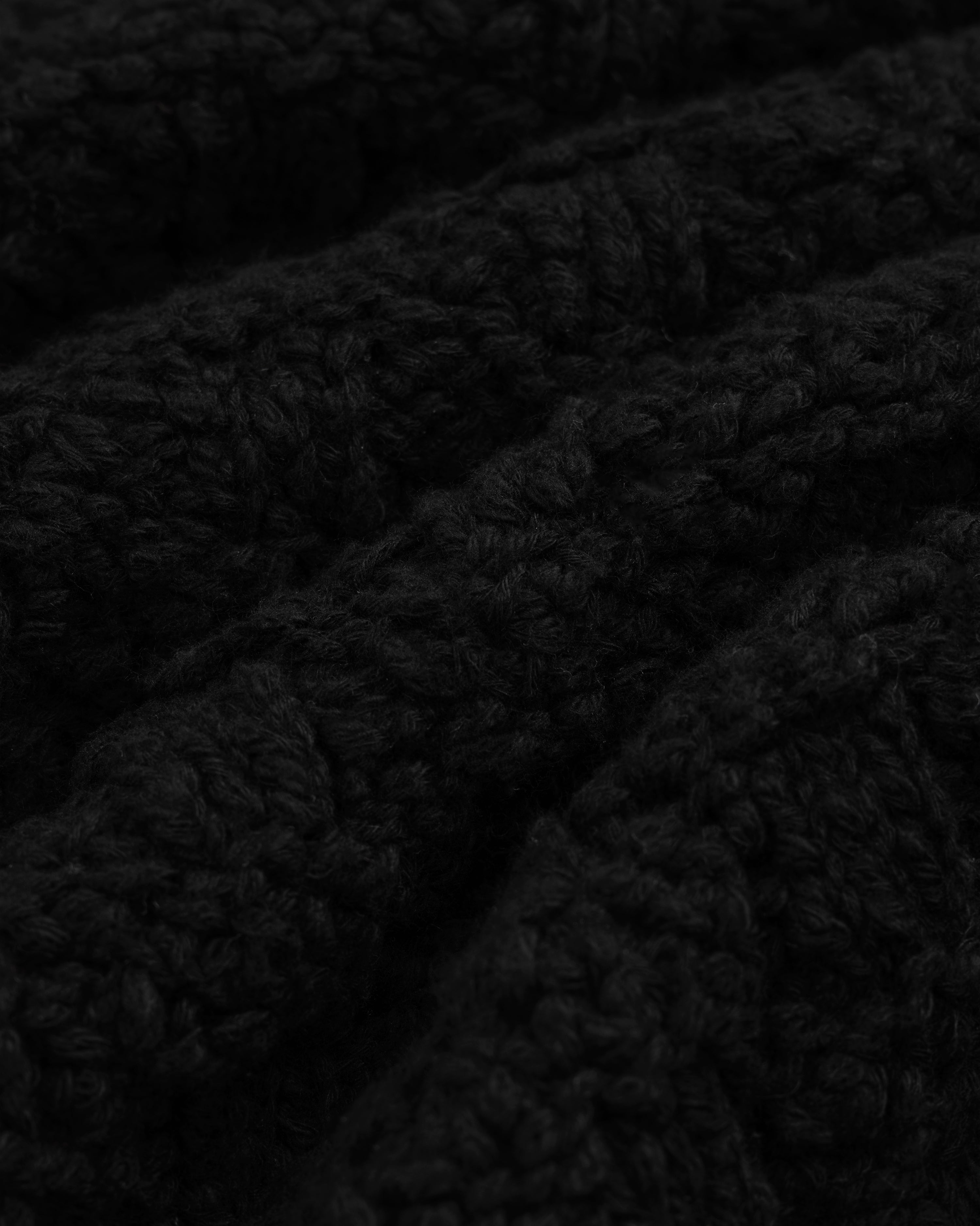 Close-up of a black Checkerboard Bouclé Sweater with a textured, looped knit pattern.