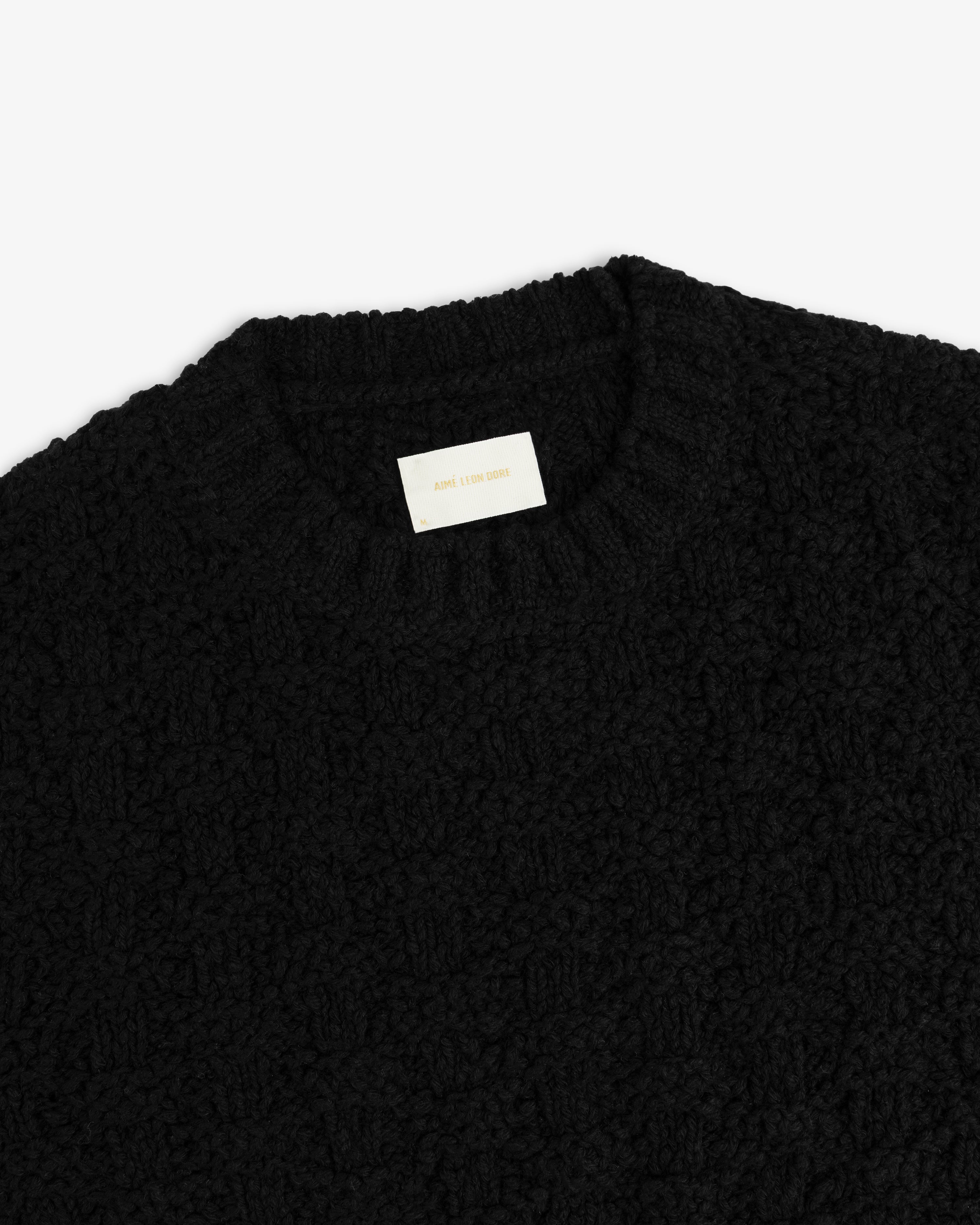 Checkerboard Bouclé Sweater in black with a textured knit, ribbed crew neck, and white interior brand label.