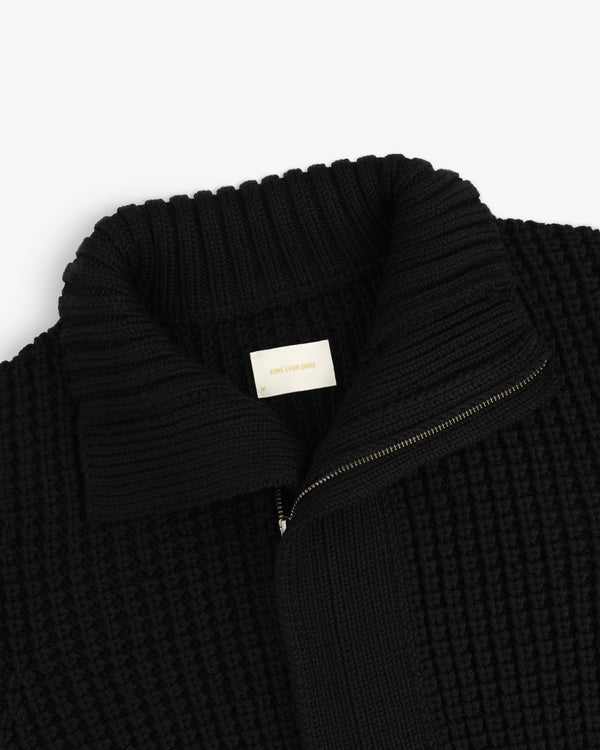 Black ribbed knit Merino Wool Full Zip Sweater with a high collar and an interior brand label.