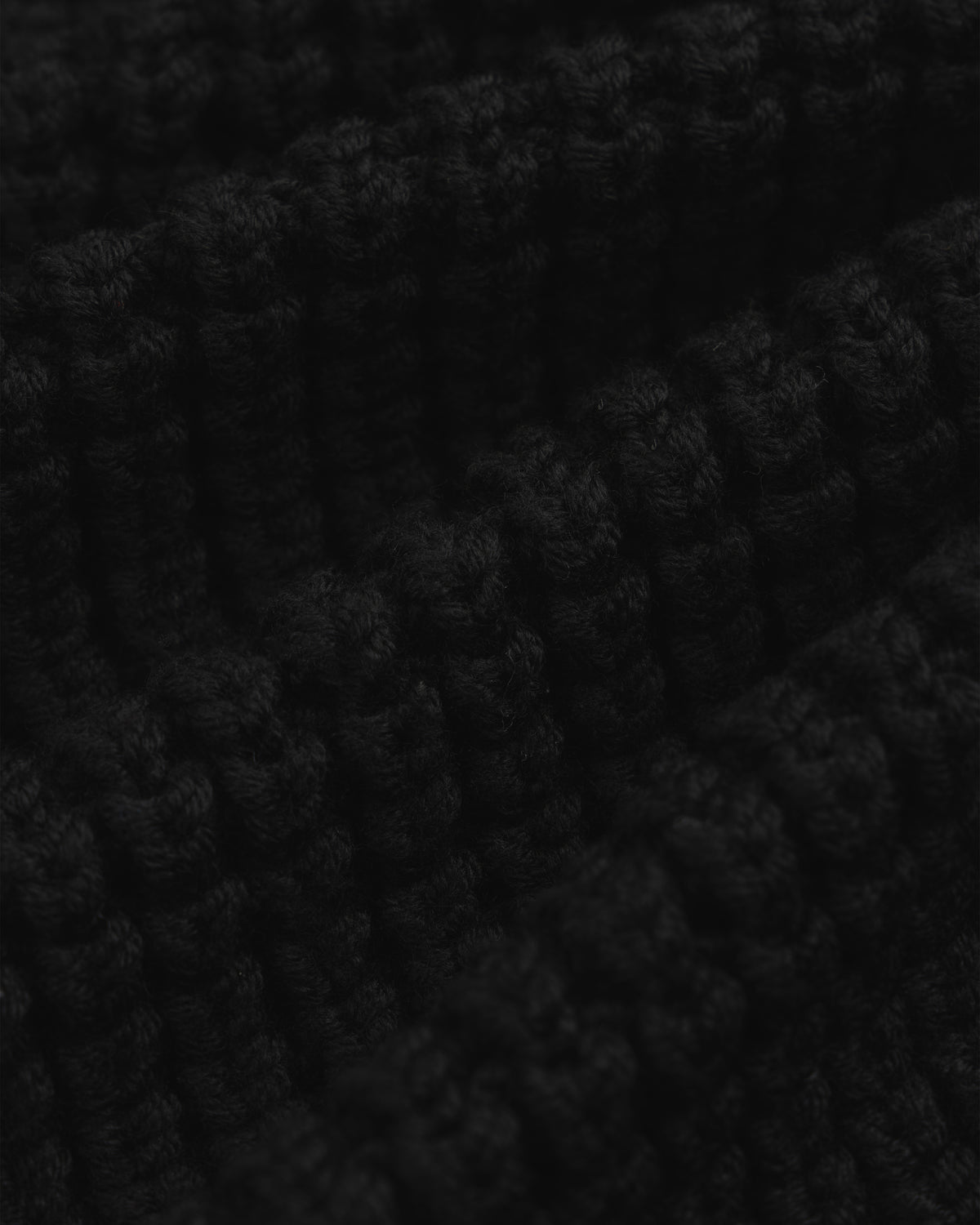 Close-up of a black chunky ribbed knit Merino Wool Full Zip Sweater.