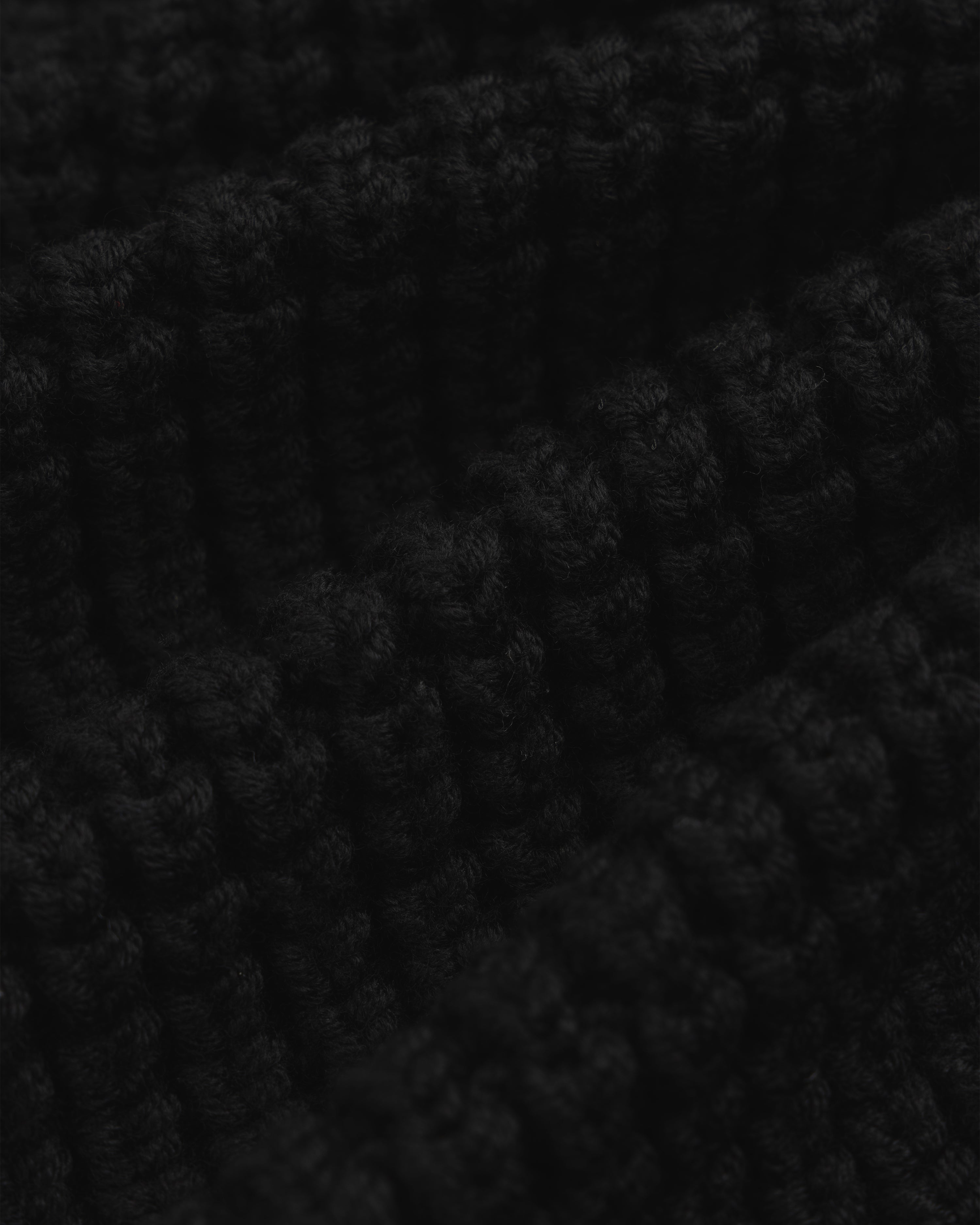 Close-up of a black chunky ribbed knit Merino Wool Full Zip Sweater.