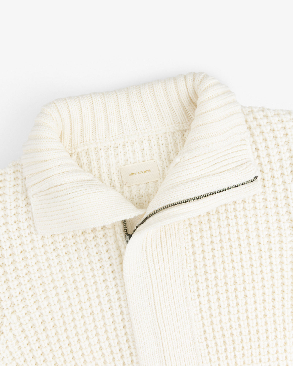 Merino Wool Full Zip Sweater in off-white knit with a ribbed collar and a half-zip front.