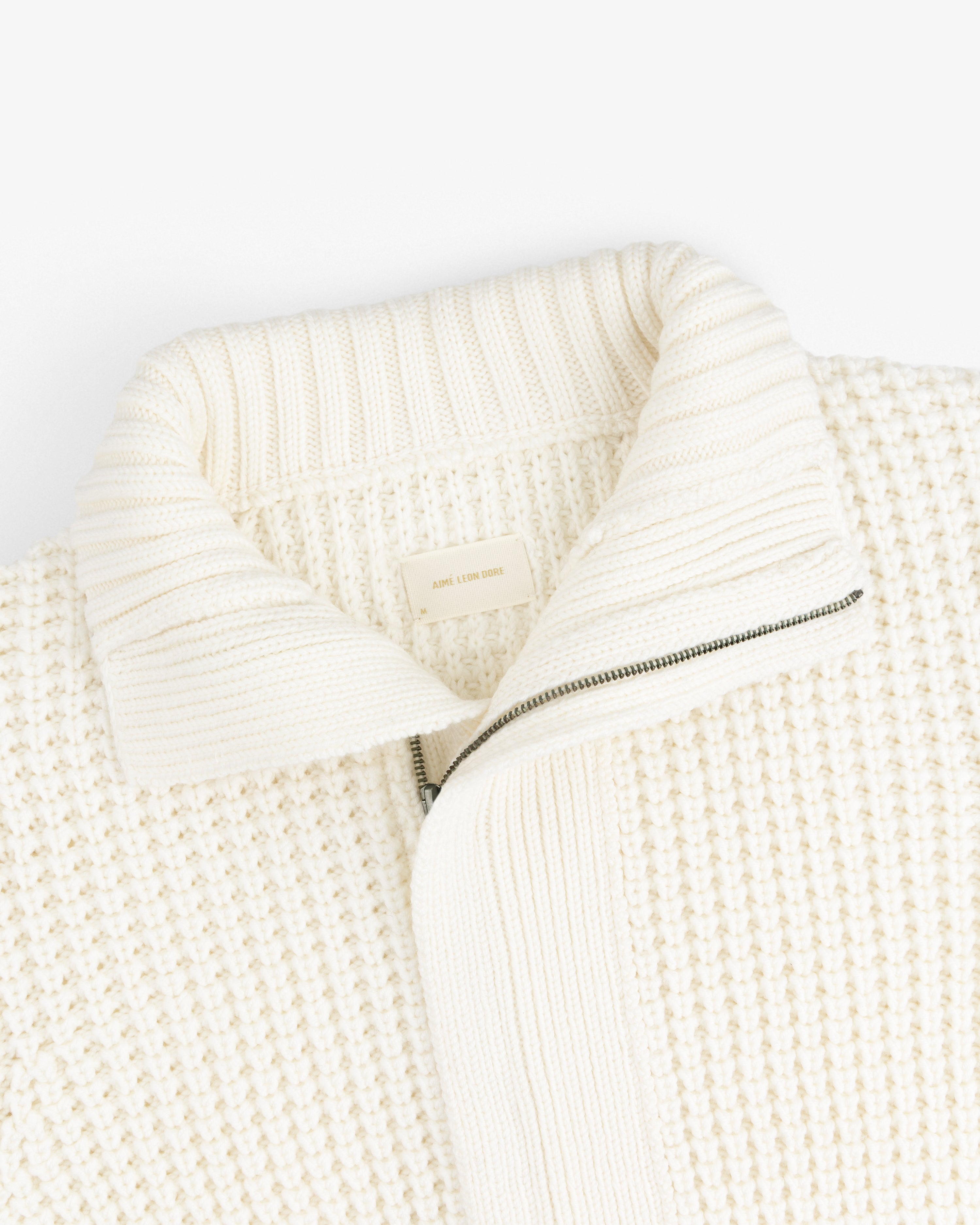 Merino Wool Full Zip Sweater in off-white knit with a ribbed collar and a half-zip front.