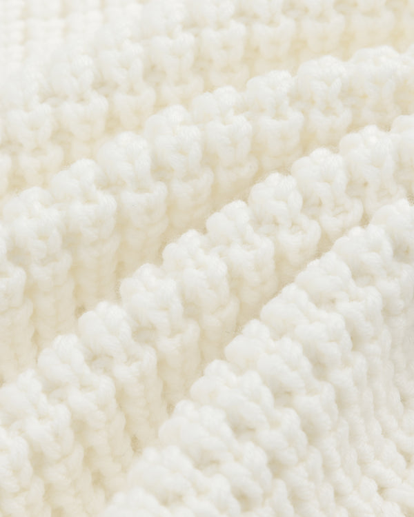 Close-up of a white Merino Wool Full Zip Sweater showing ribbed knit fabric with soft, vertical folds.