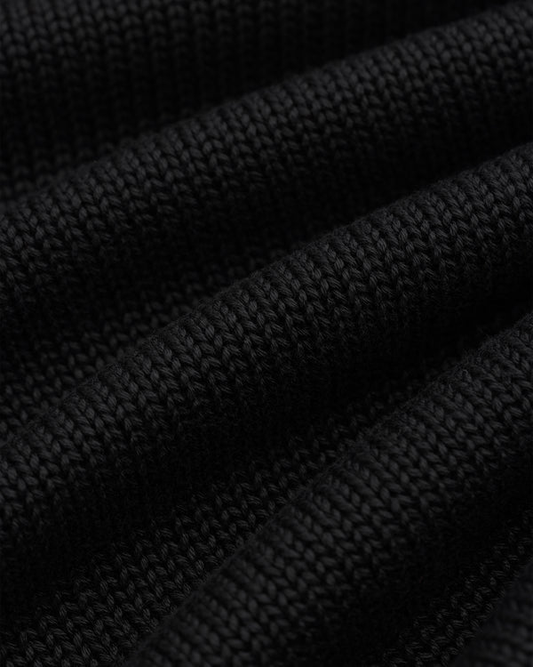 Close-up of black Knit Pocket Crewneck Sweater fabric with deep folds.