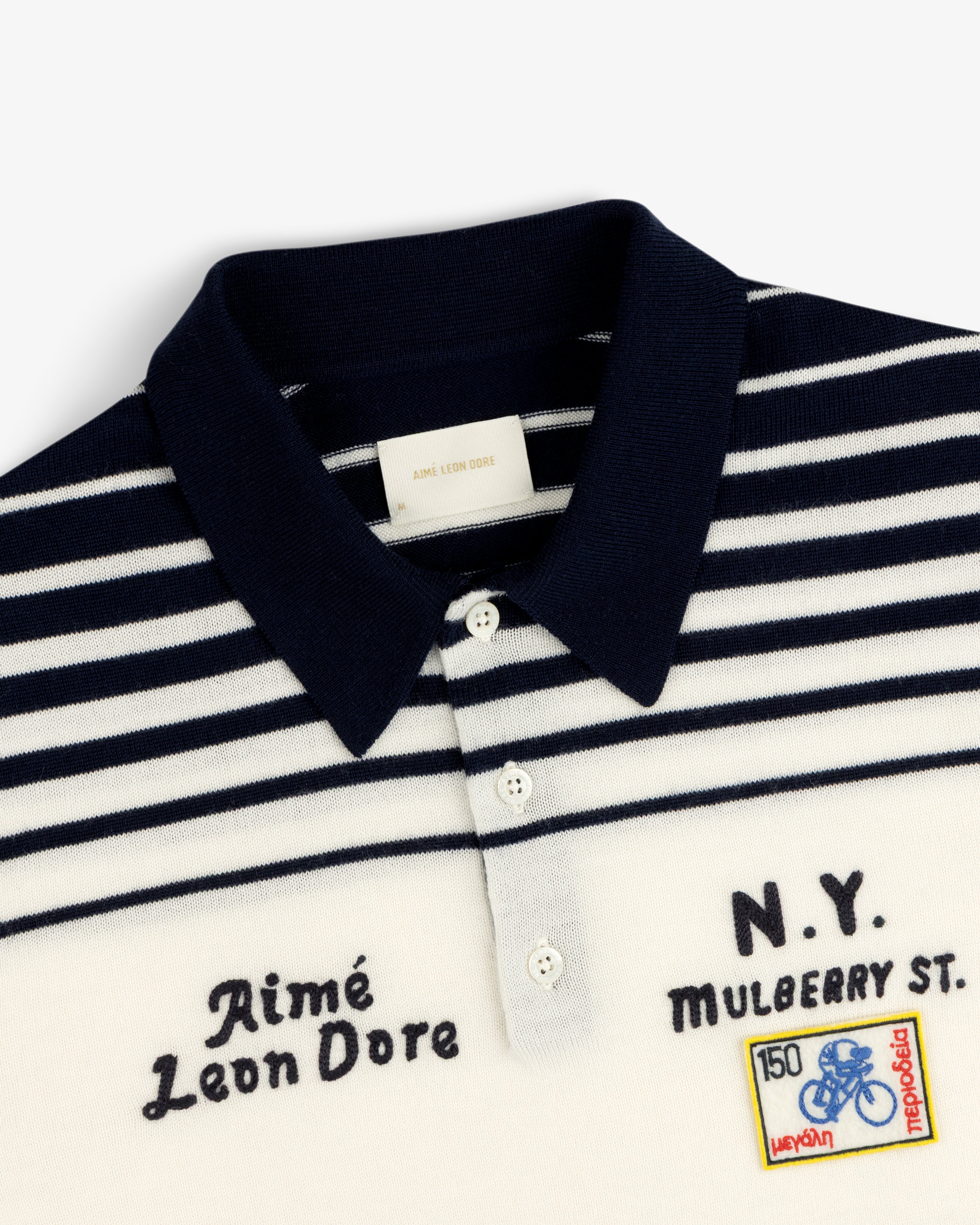 Merino Wool Knit Cycling Polo with navy and white stripes, embroidered patches, and Aimé Leon Dore text.