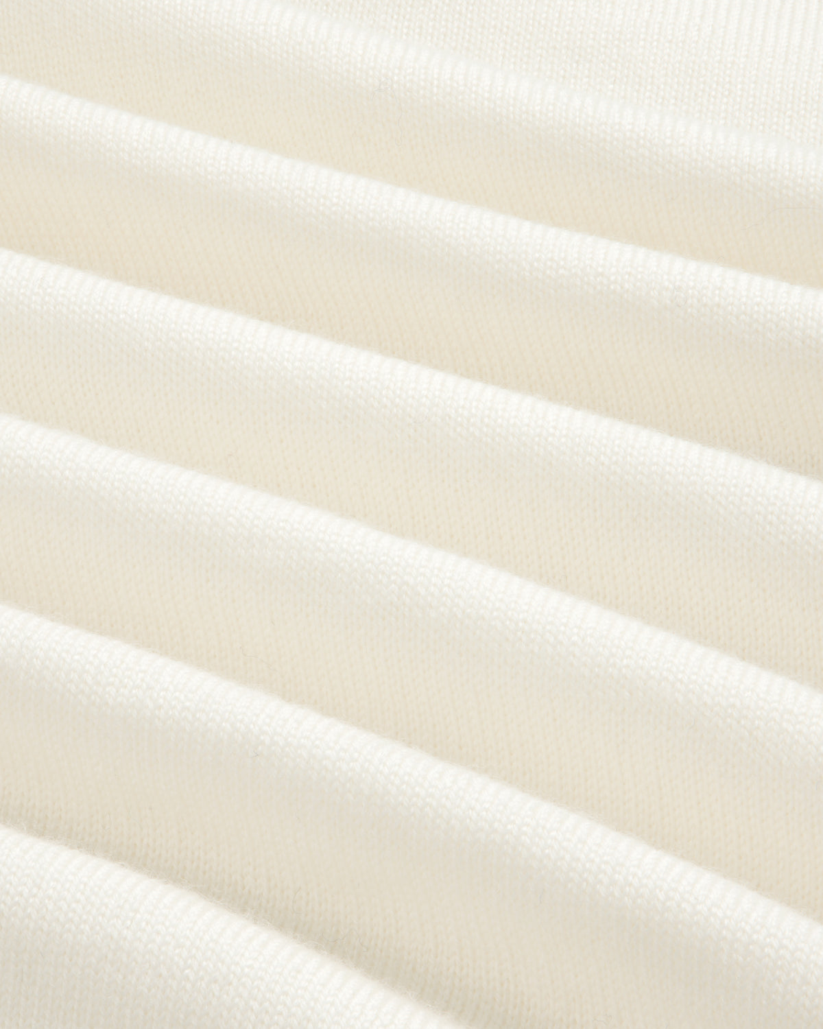 Close-up of Merino Wool Knit Cycling Polo’s soft, cream fabric with gentle folds and subtle ribbed texture.