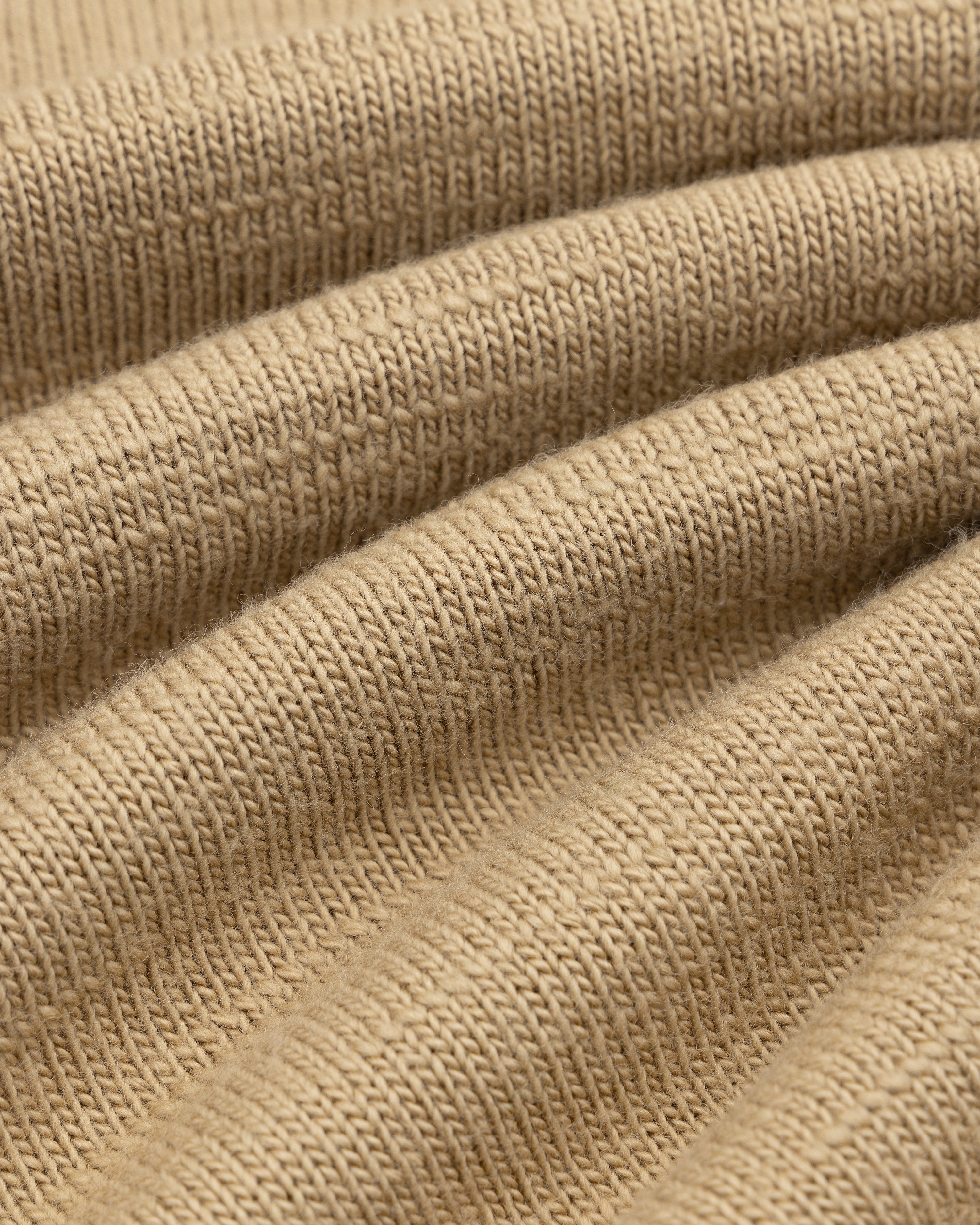 Close-up of tan Slub Merino Wool Sweater knit fabric with textured diagonal folds.