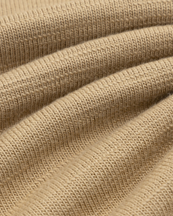 Close-up of tan Slub Merino Wool Sweater knit fabric with textured diagonal folds.