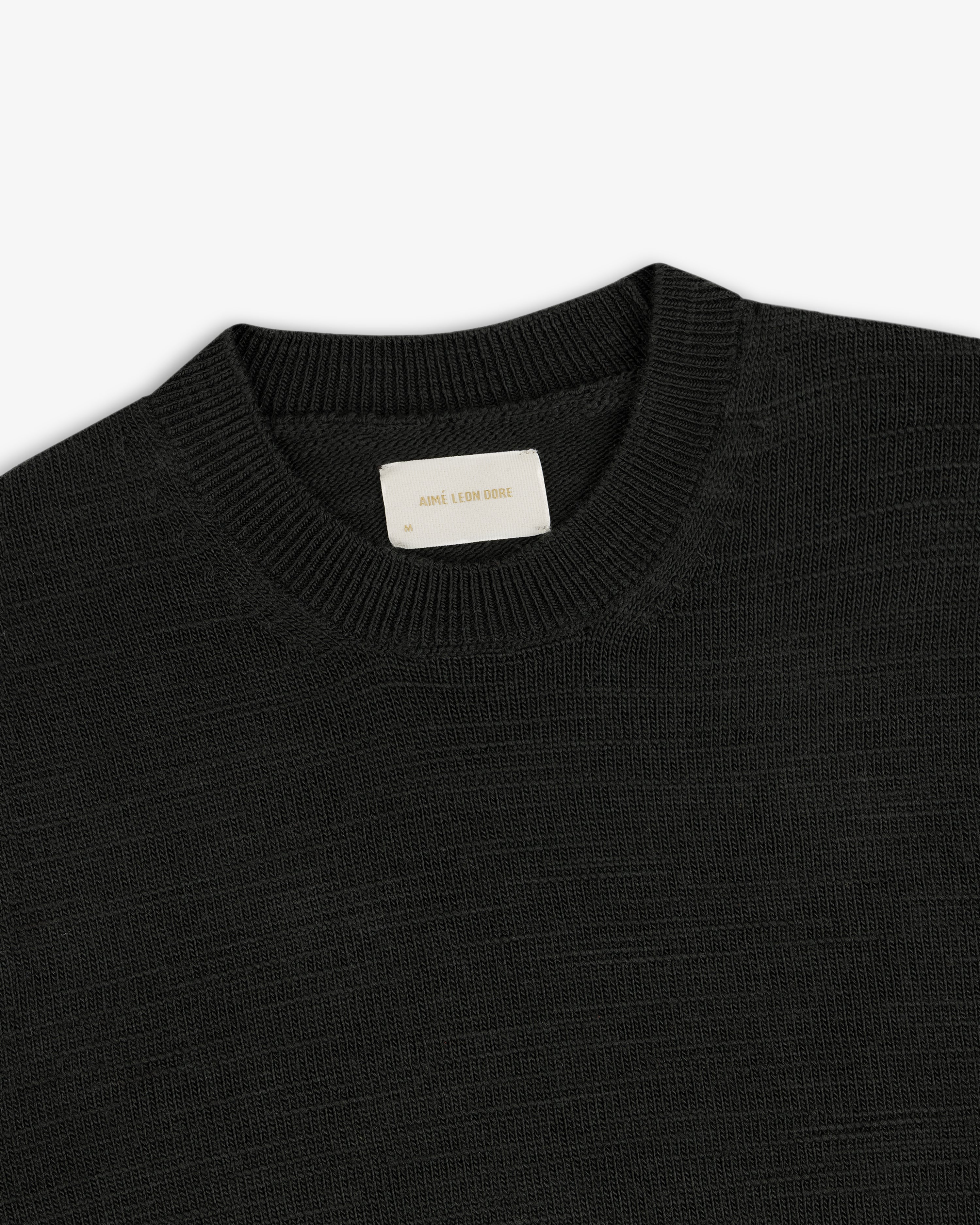 Black Slub Merino Wool sweater with a textured knit and an interior brand label at the collar.
