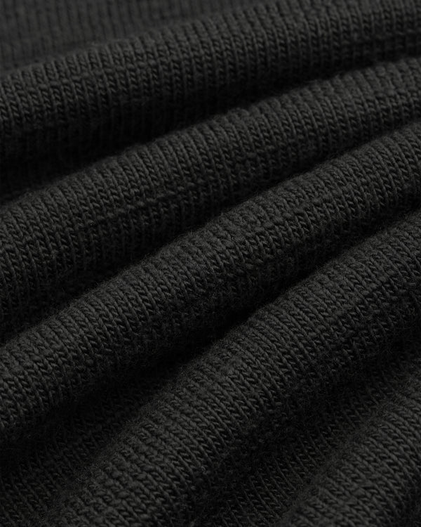 Close-up of black Slub Merino Wool Sweater knit fabric with visible texture and folds.