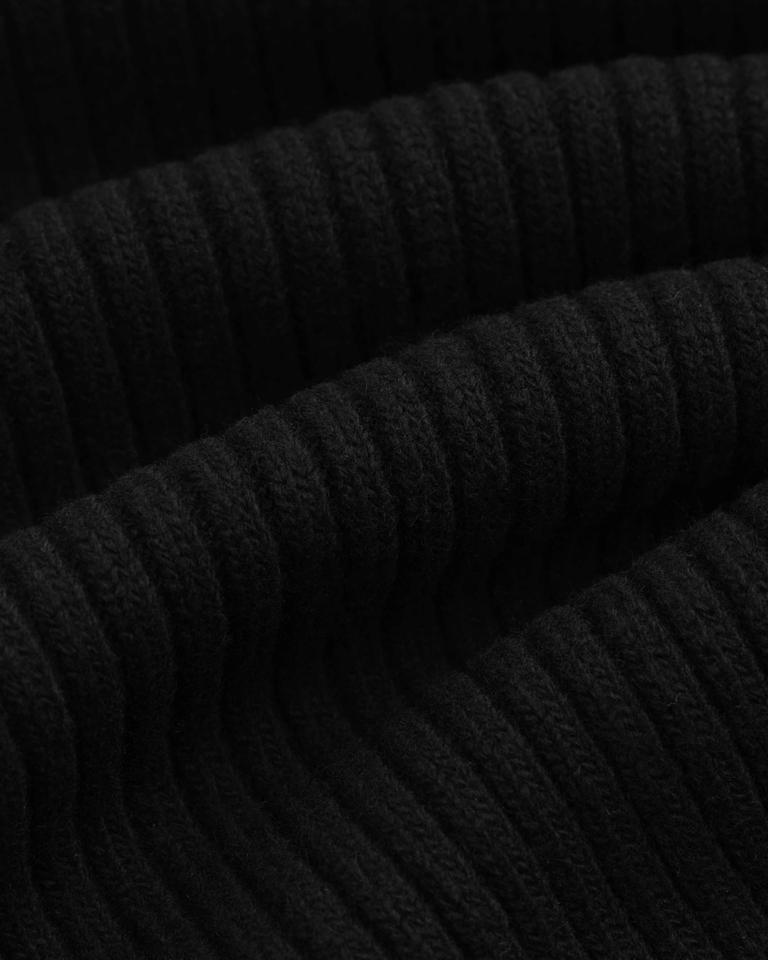 Close-up of the black ribbed knit fabric of a Wool Ribbed Knit Hoodie.