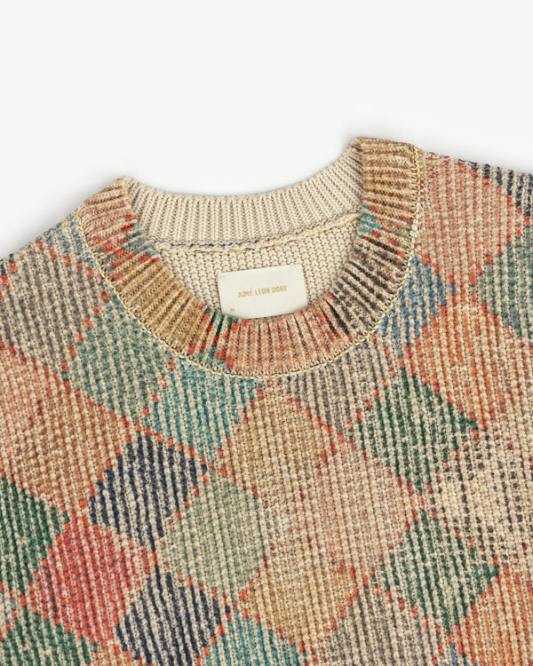 Close-up of the Kilim Argyle Crewneck Sweater, featuring a multicolored argyle pattern and beige collar.