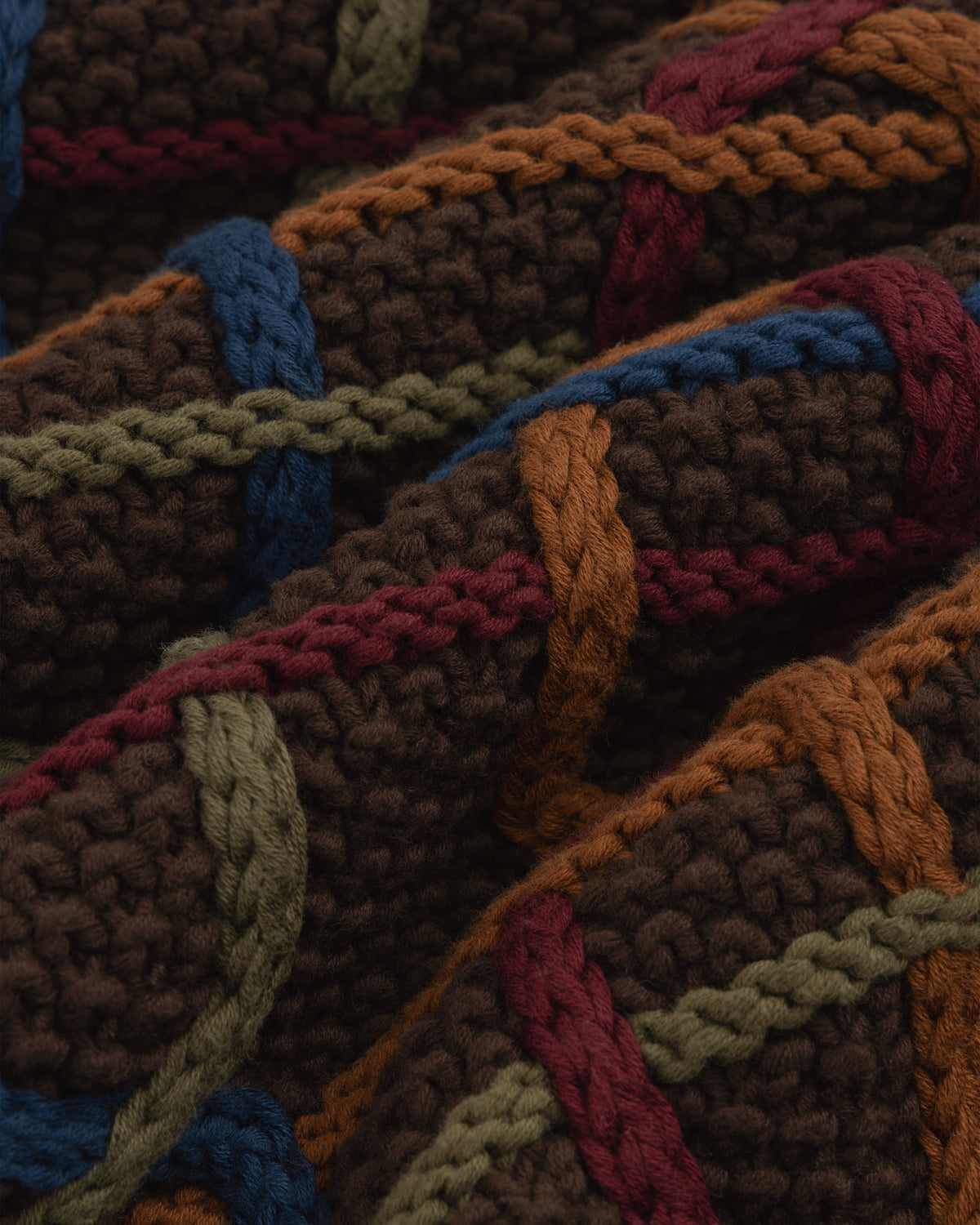 Close-up of a Cable Link Crewneck Sweater in brown with a raised cable pattern in blue, green, orange, and red.
