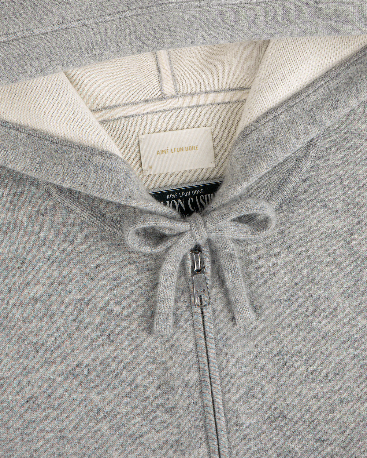 Close-up of the Full-Zip Pavilion Cashmere Hoodie in gray, featuring a tied drawstring and collar tags.
