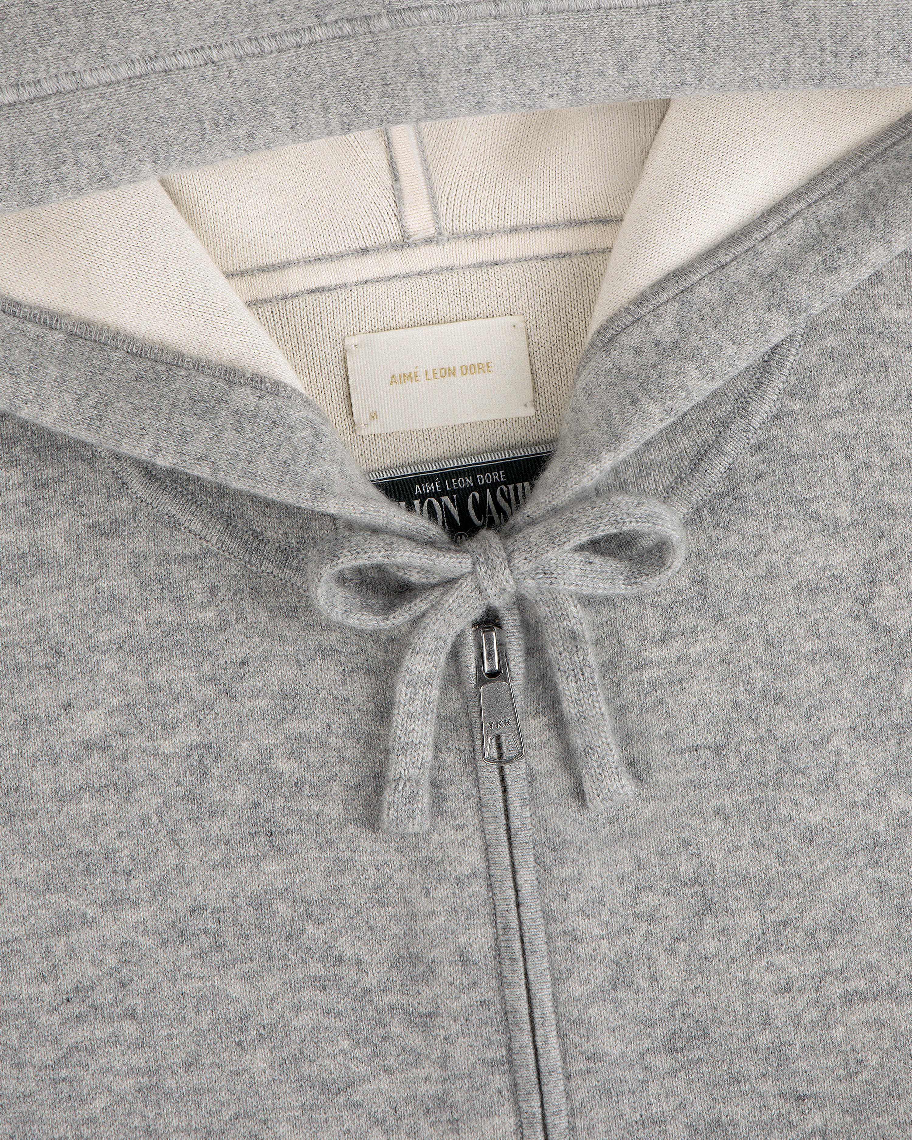 Close-up of the Full-Zip Pavilion Cashmere Hoodie in gray, featuring a tied drawstring and collar tags.