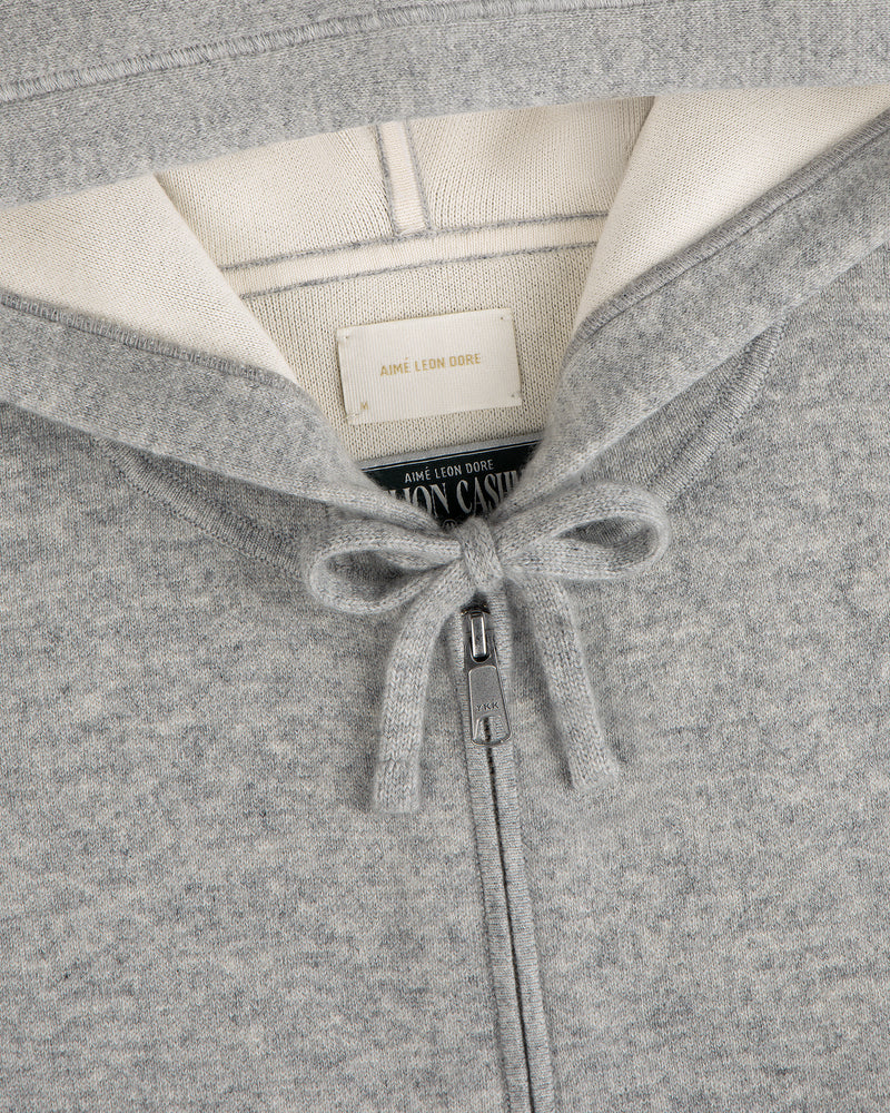 Close-up of the Full-Zip Pavilion Cashmere Hoodie in gray, featuring a tied drawstring and collar tags.