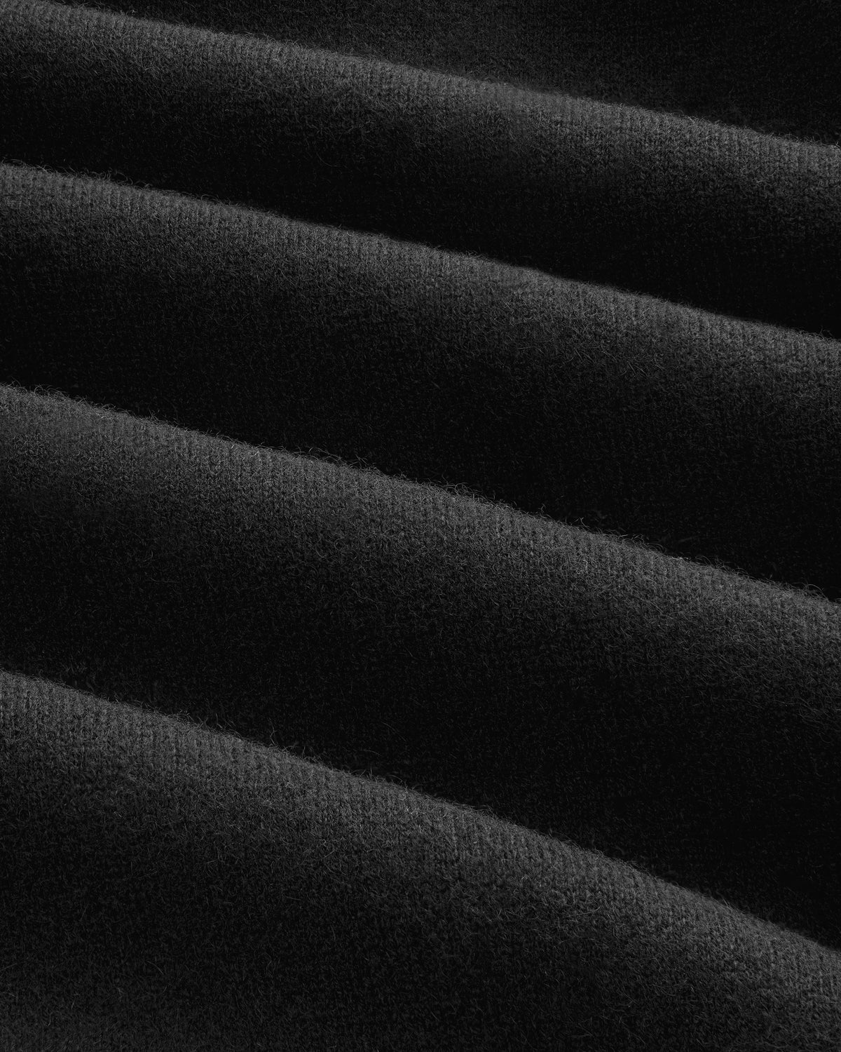 Close-up of Pavilion Cashmere Sweatpant: soft black fabric with even horizontal ridges and a velvety texture.