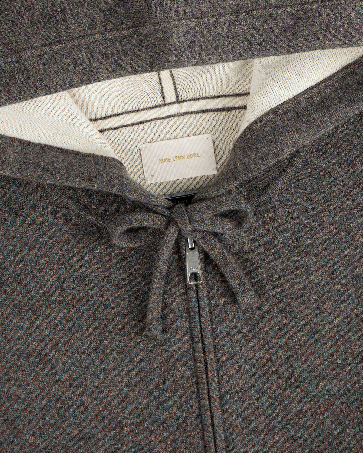 Close-up of a brown Full-Zip Pavilion Cashmere Hoodie with drawstring and visible Aimé Leon Dore label in the collar.