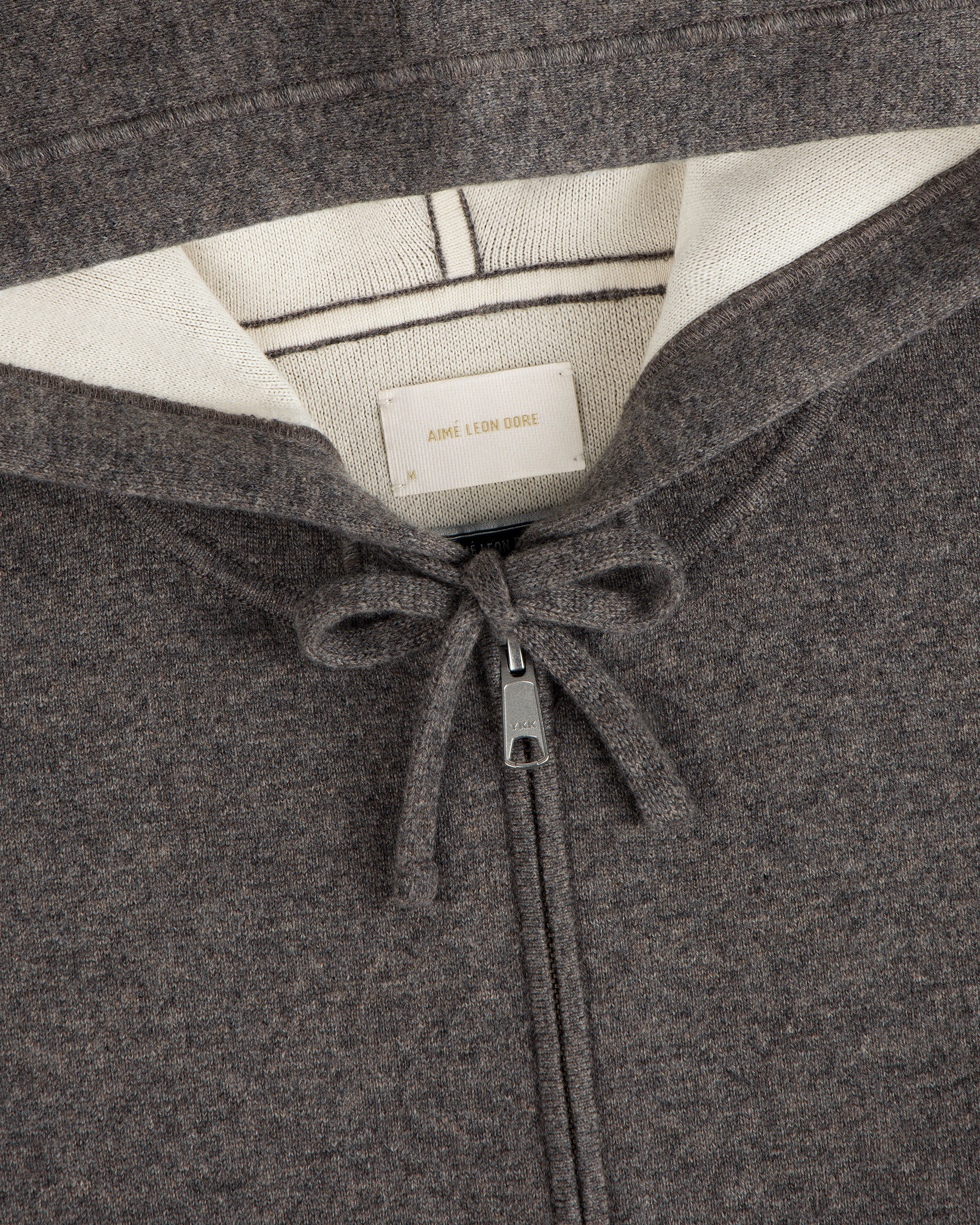 Close-up of a brown Full-Zip Pavilion Cashmere Hoodie with drawstring and visible Aimé Leon Dore label in the collar.