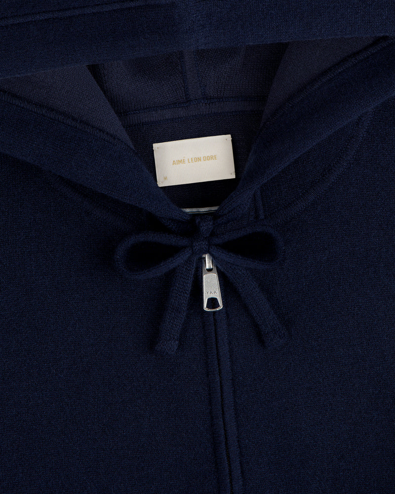 Close-up of the Full-Zip Pavilion Cashmere Hoodie in navy blue, featuring a zipper, drawstring, and beige collar label.