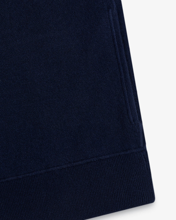Close-up of a Quarter Zip Pavilion Cashmere Pullover in navy blue with pocket and ribbed hem on white background.
