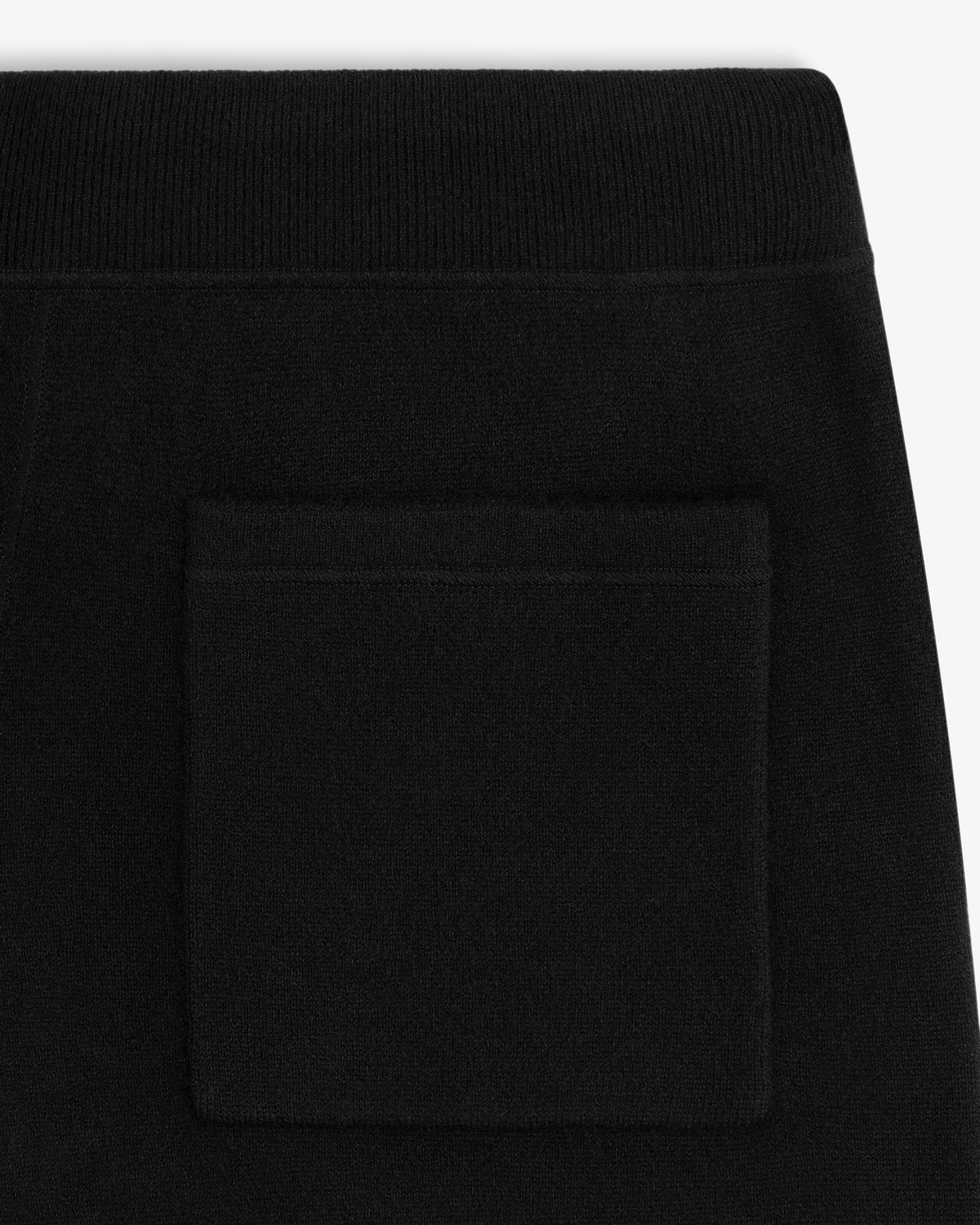 Close-up of Pavilion Cashmere Sweatpant in black, showing a square patch pocket and ribbed waistband detail.