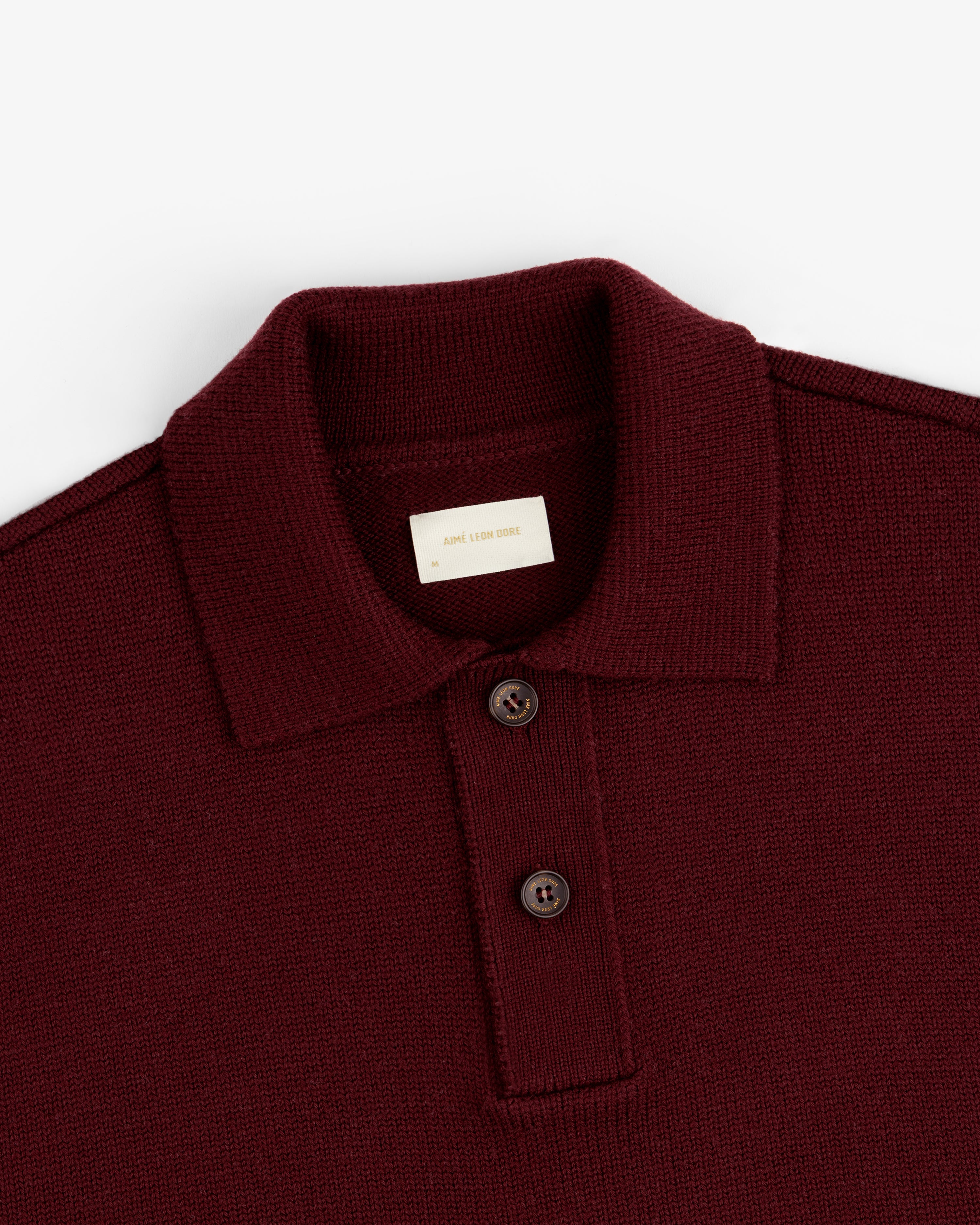 Close-up of a burgundy Long-Sleeve Merino Polo featuring a knit fabric and a two-button placket.
