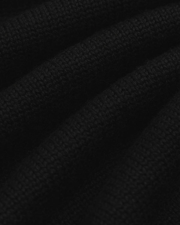 Close-up of black knit fabric from a Long-Sleeve Merino Polo with diagonal folds.
